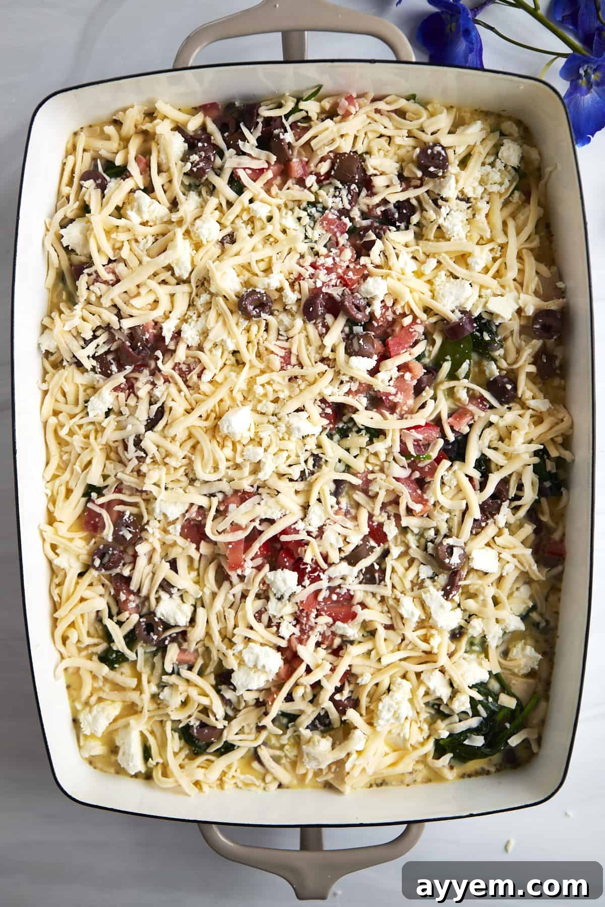 A rich mixture of feta and mozzarella cheese generously topping the egg and vegetable mixture, ready for the oven.