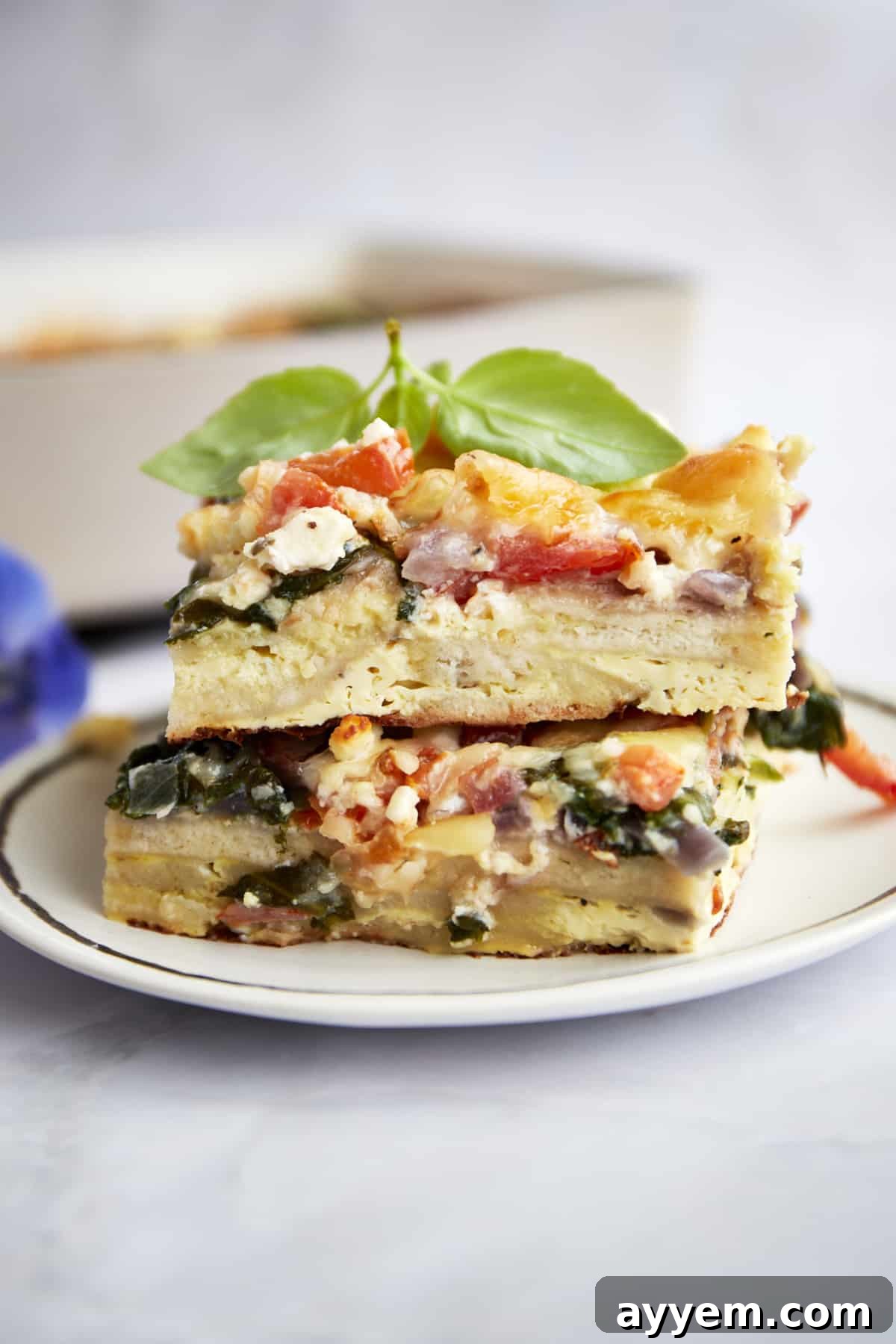 Two slices of the Greek egg bake casserole presented on a plate, showcasing its fluffy texture and rich layers.
