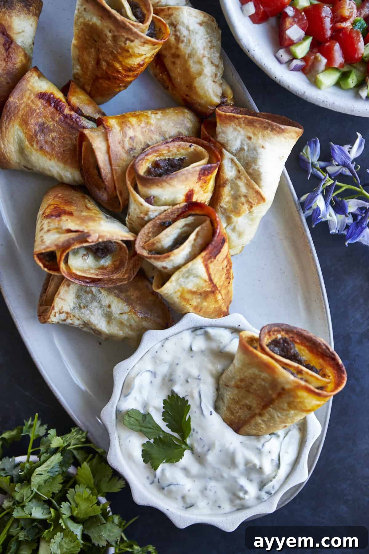 A platter of beef rolls with a side of tzatziki.