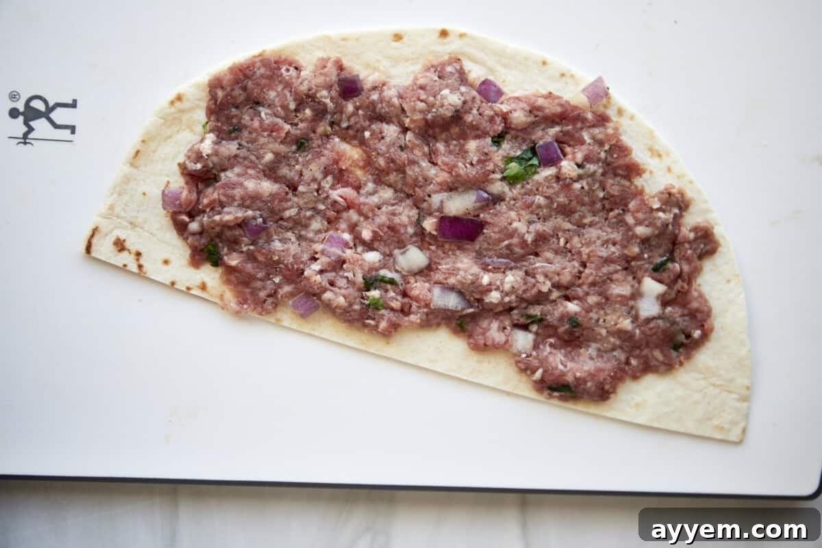 Ground beef spread over a tortilla half.