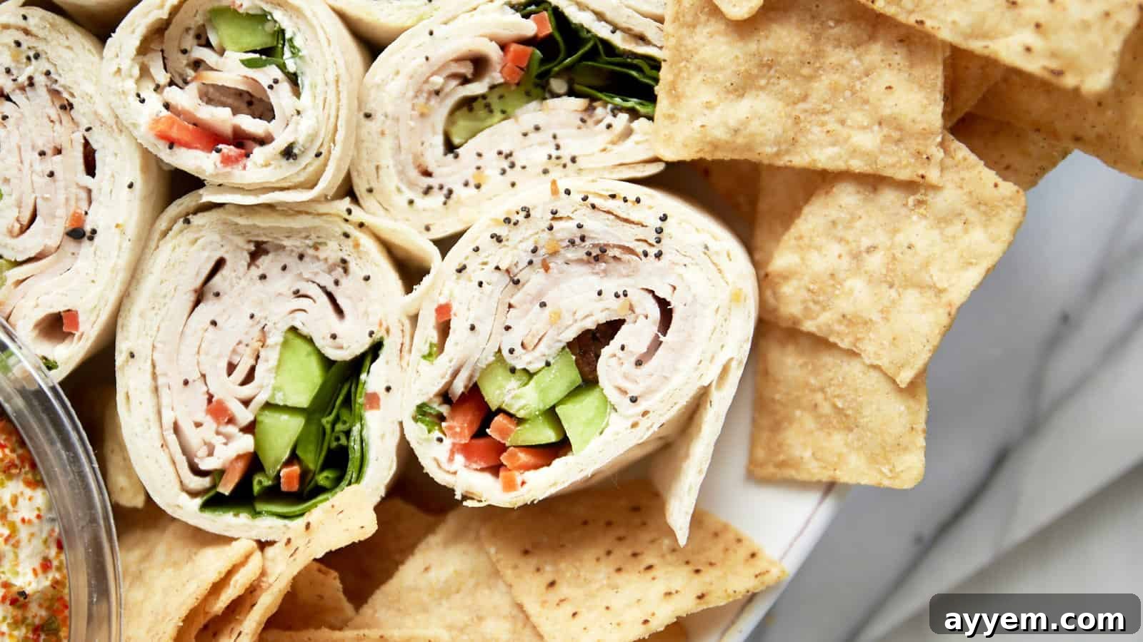 Colorful turkey pinwheel sandwiches arranged on a serving platter with fresh herbs.