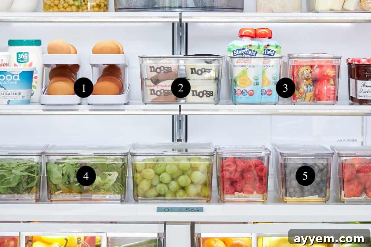 A neatly organized refrigerator section featuring an egg dispenser, clear storage bins, and berry containers.