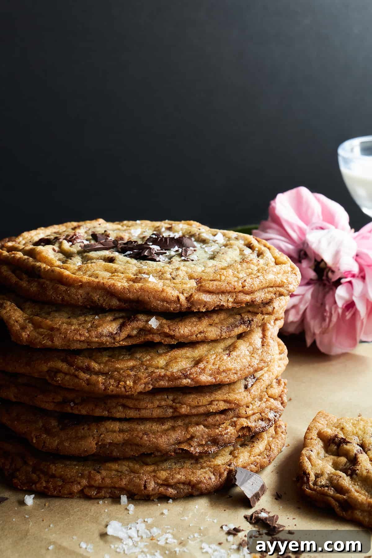 A stack of six pan banging chocolate chip cookies, each with visible crinkled edges and melting chocolate chips.