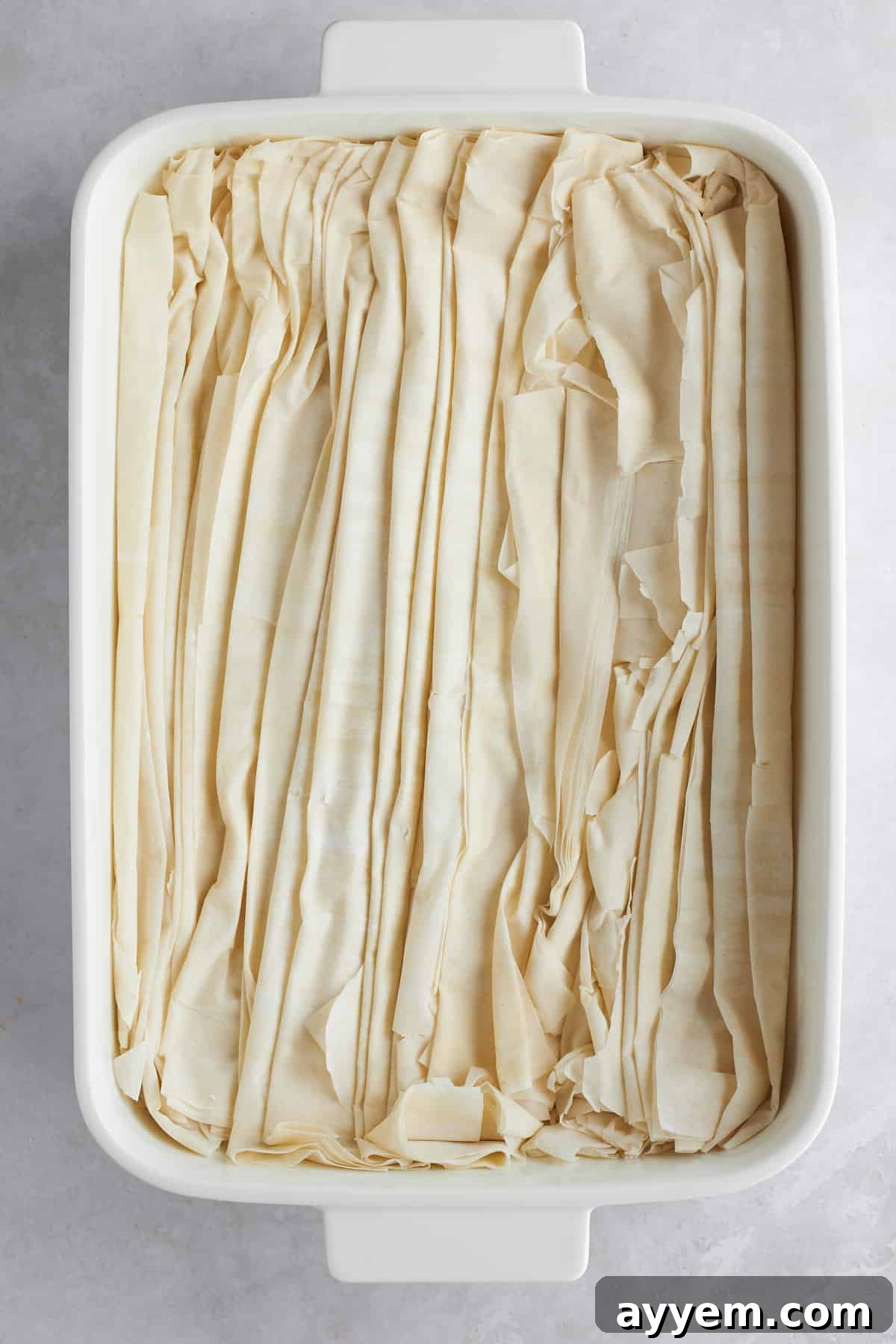 A baking dish filled with neatly arranged scrunched phyllo dough, ready for baking.