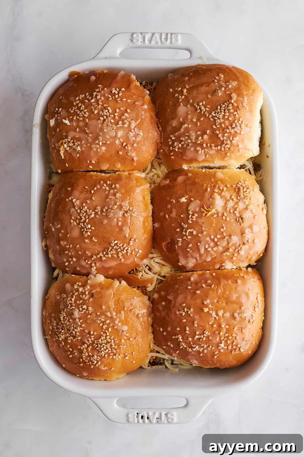 Unbaked ground beef sliders in a baking dish. 