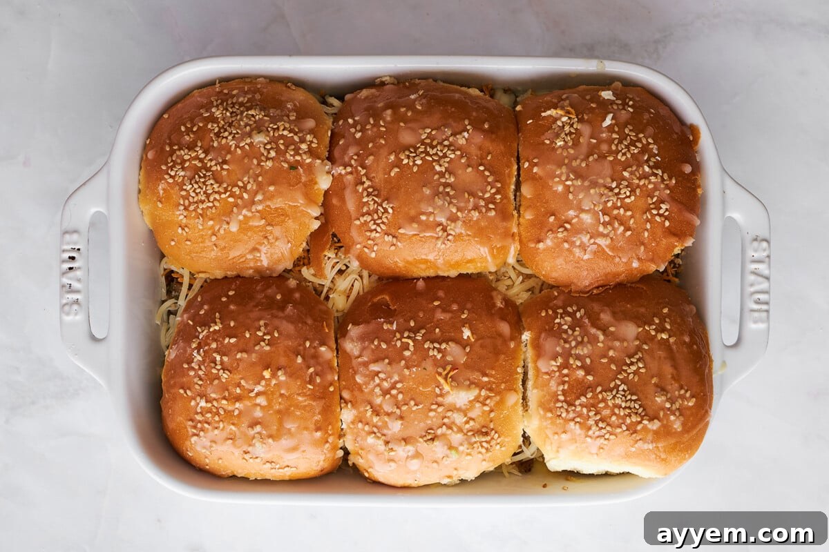 Unbaked ground beef sliders with cheese in a baking dish.
