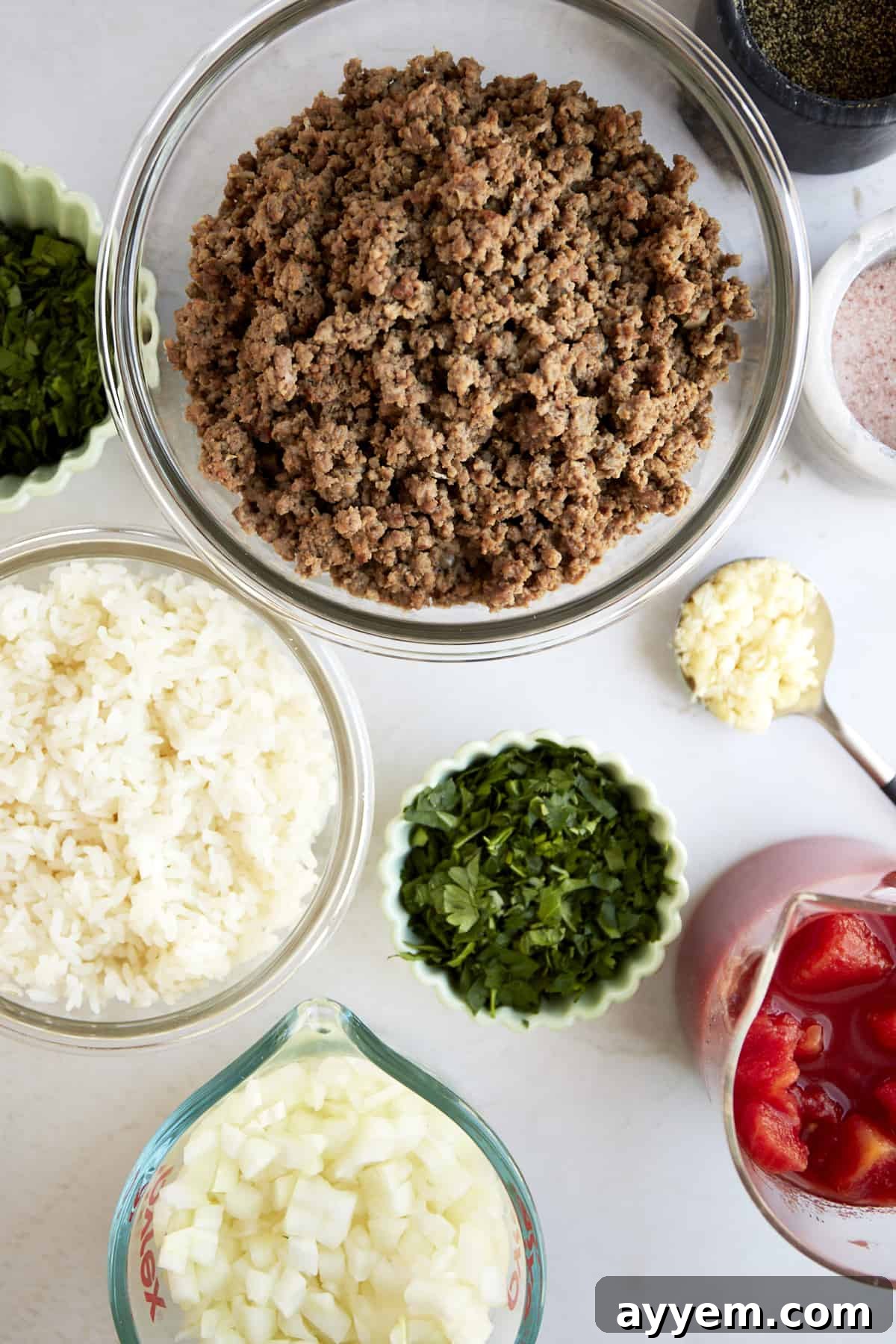 A selection of fresh ingredients laid out for making slow cooker Mediterranean stuffed peppers, including bell peppers, herbs, ground beef, and canned tomatoes.
