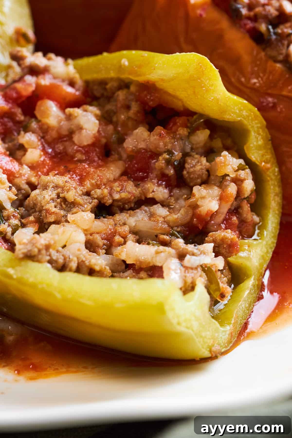 A slow cooker Mediterranean stuffed pepper expertly sliced in half, revealing the perfectly cooked beef and rice filling inside.