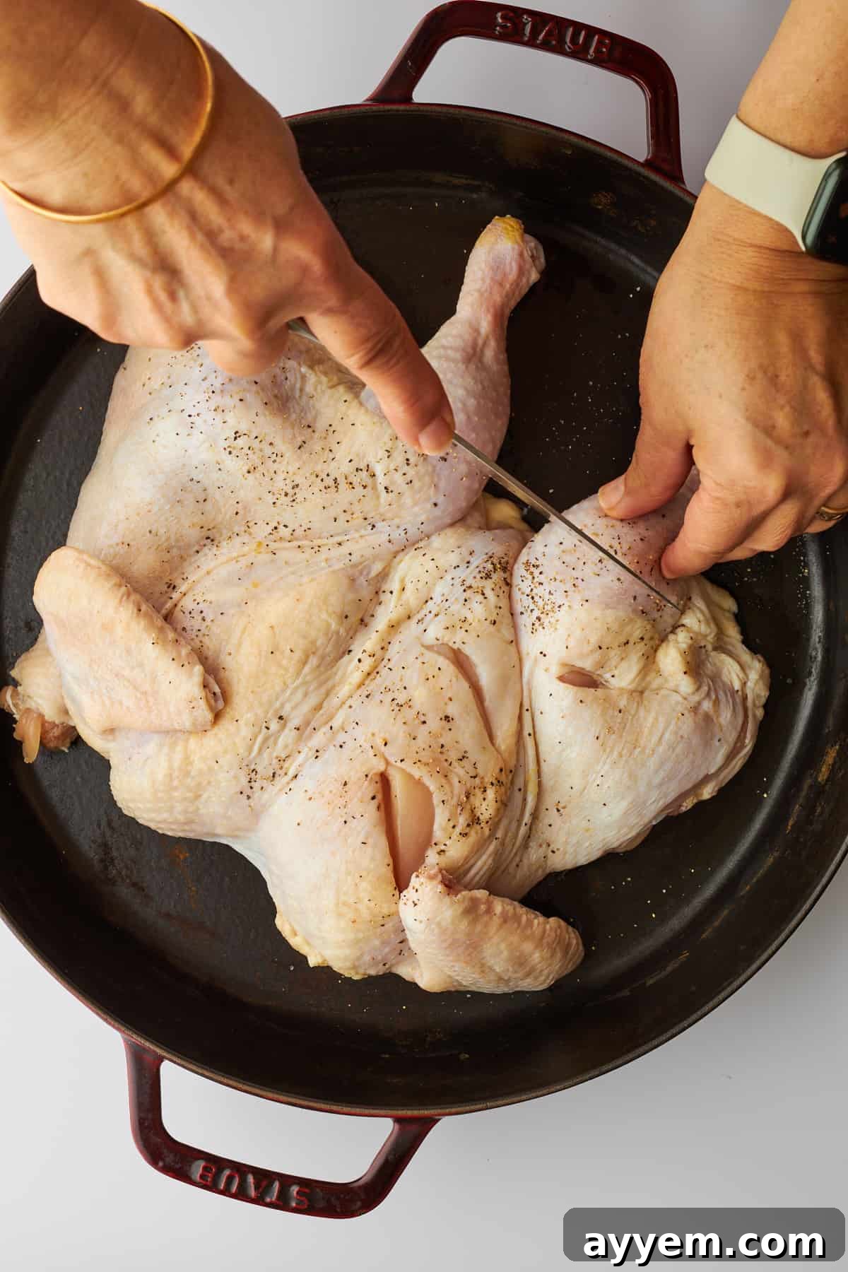 Cuts being made in the sides of a spatchcock chicken.