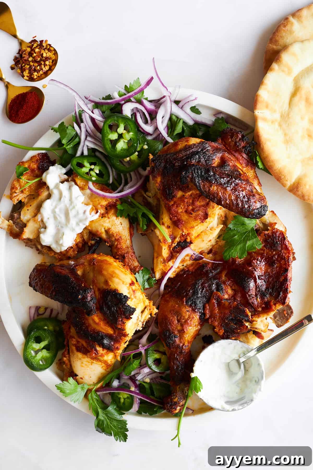 Four pieces of chicken tikka on a plate.