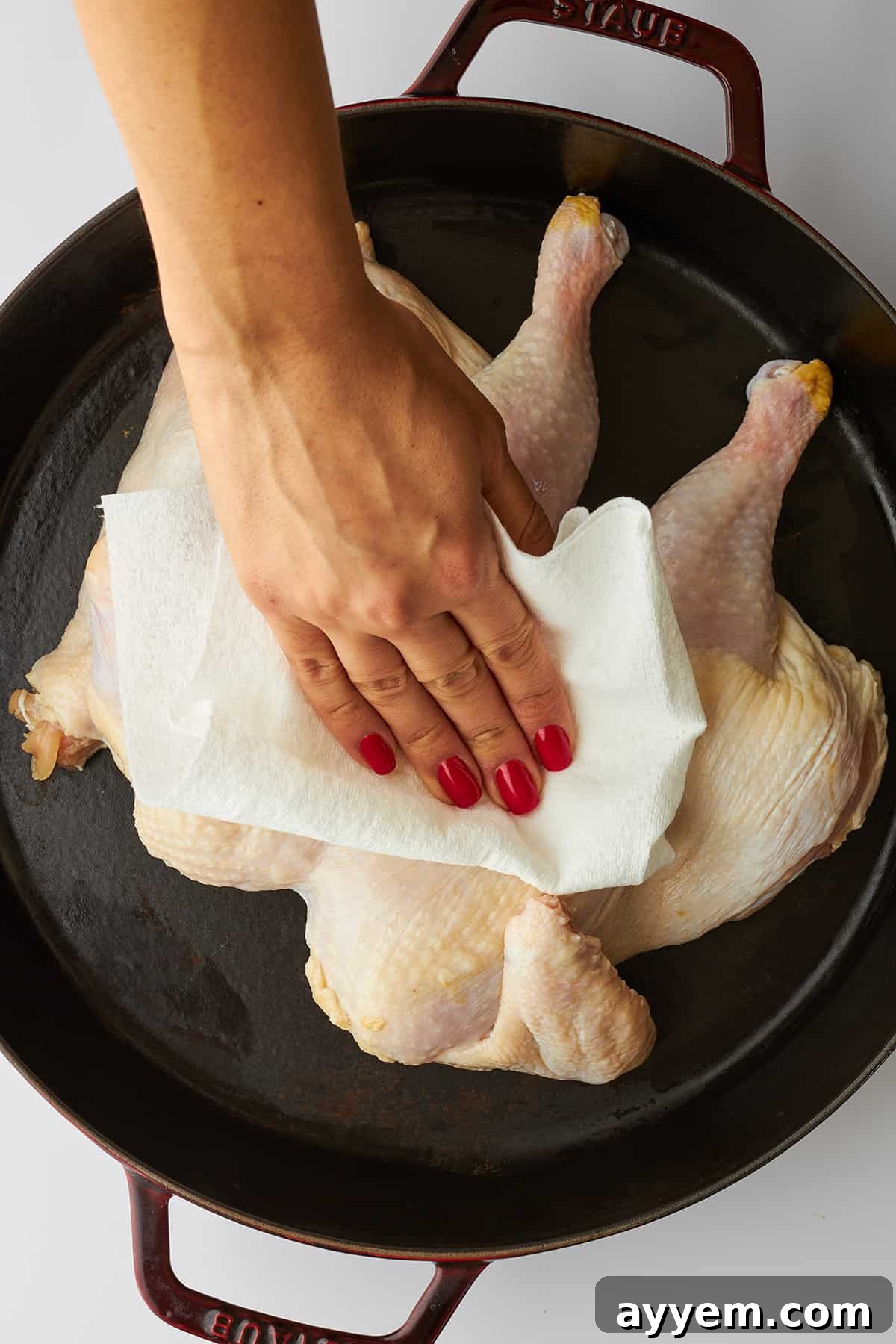 A hand drying chicken with a paper towel. 