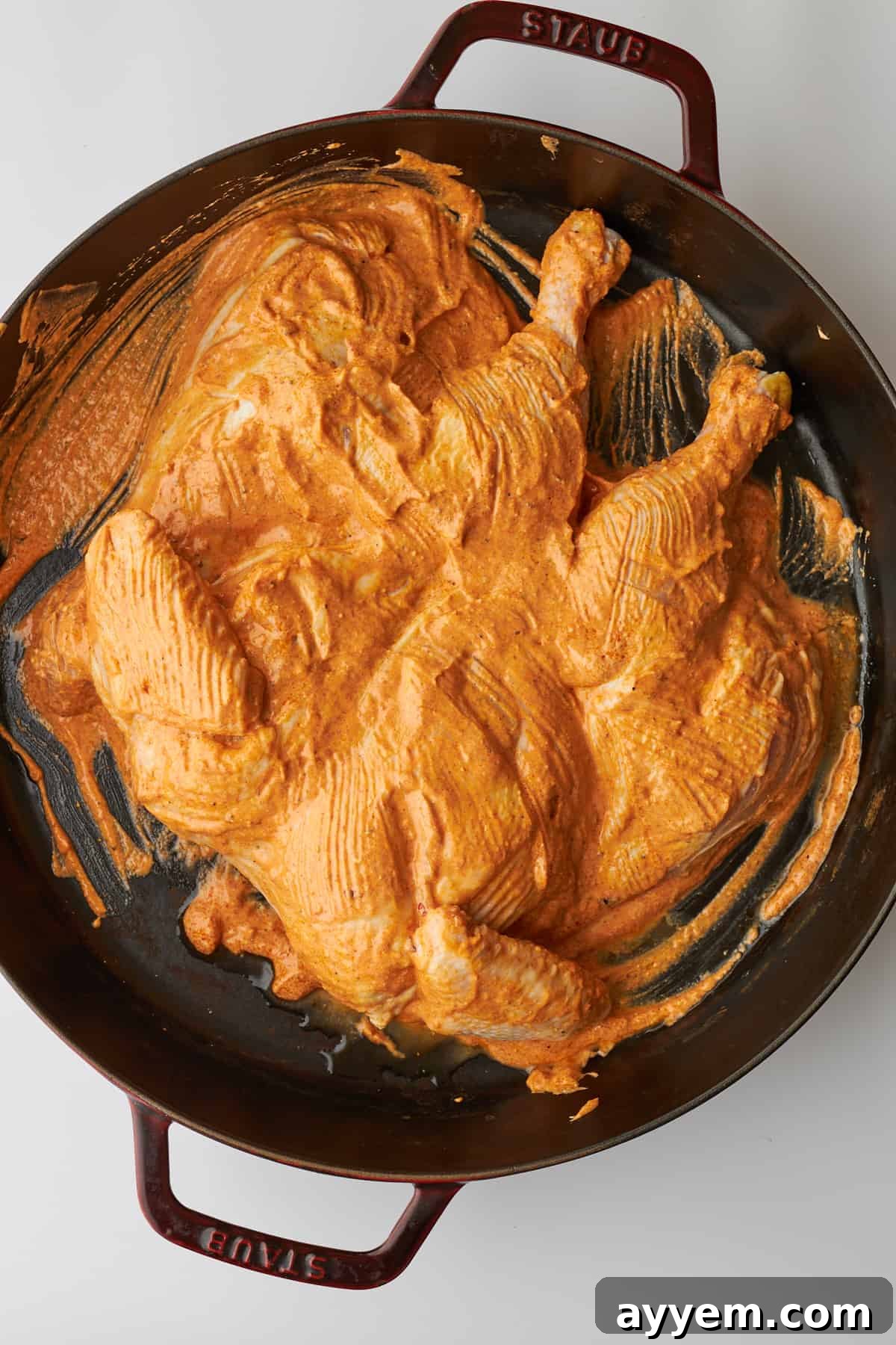 Marinated chicken tikka in a large cast iron skillet. 