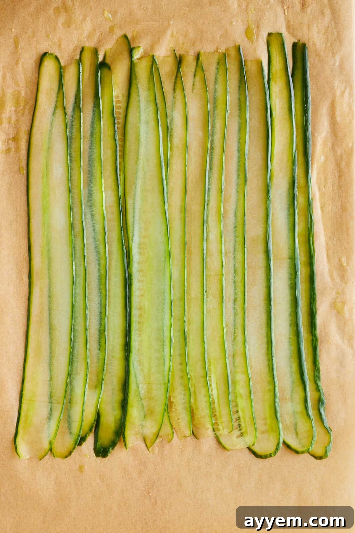 Delicate cucumber slices carefully arranged and layered over each other on a flat surface, forming a base for the rolls.