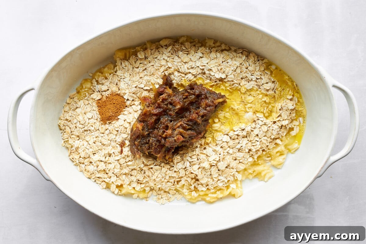 Mashed bananas, oats, date paste, and spices mixed in an oval baking dish.