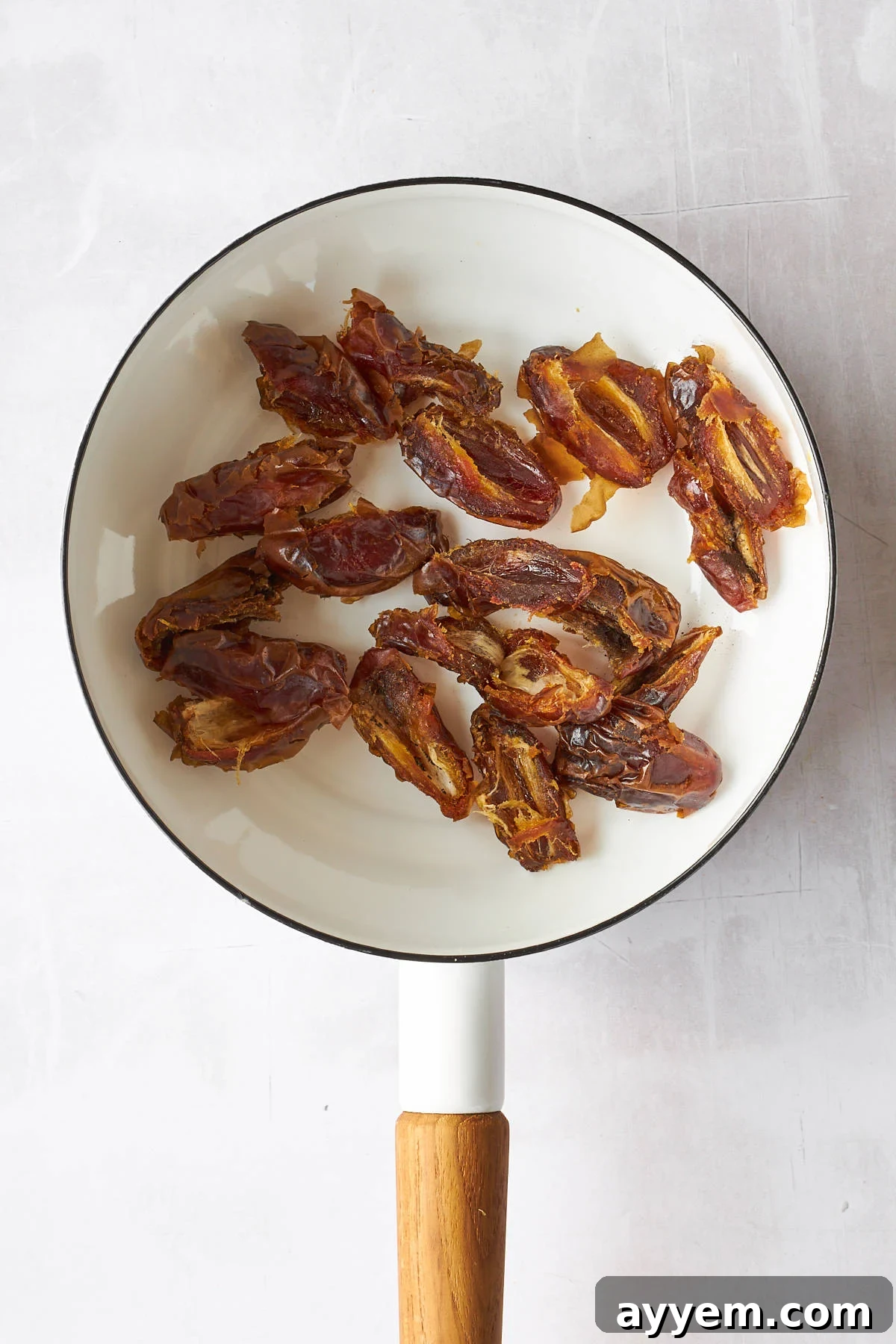 Halved dates soaking in water in a pot on the stove.