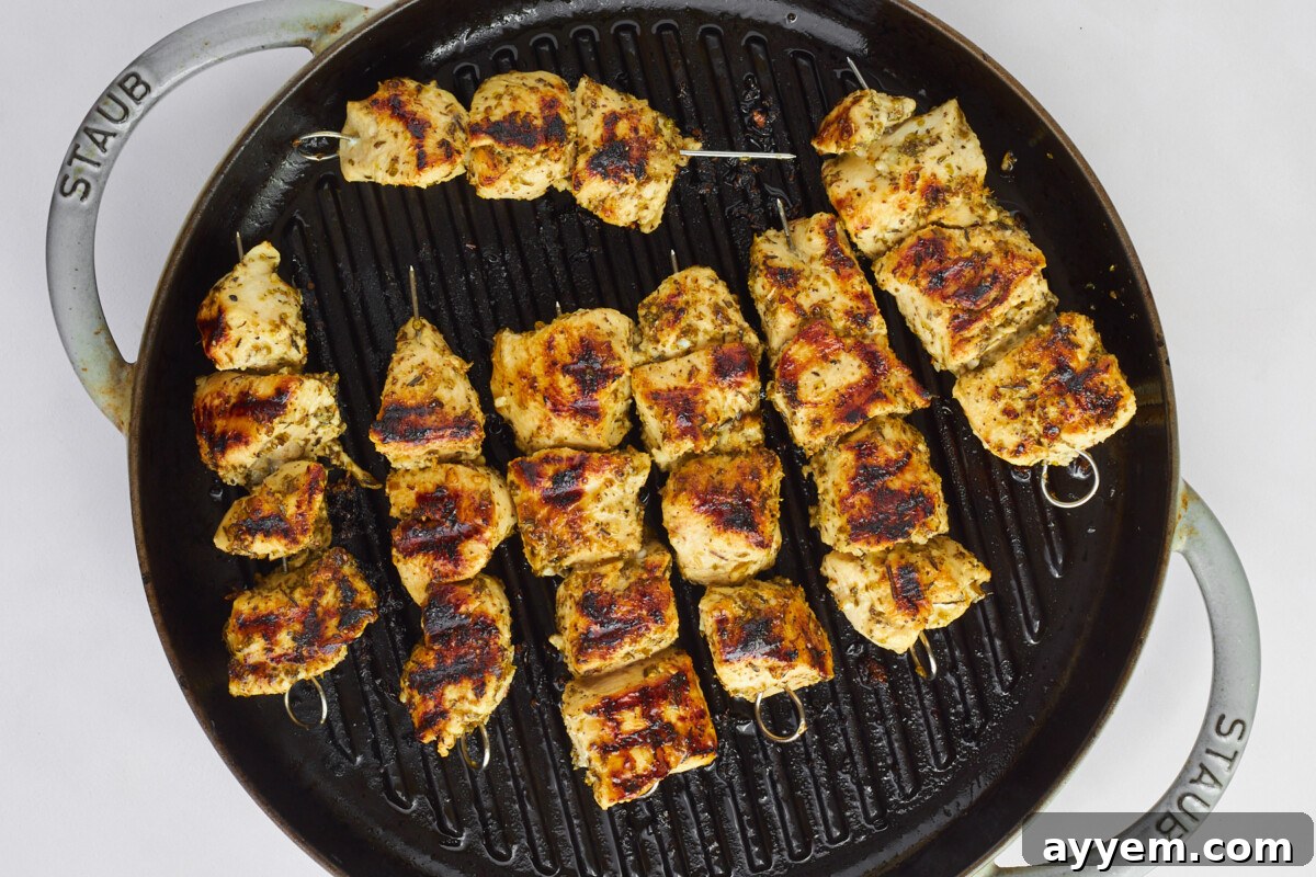 Greek chicken souvlaki skewers cooking on a grill pan.