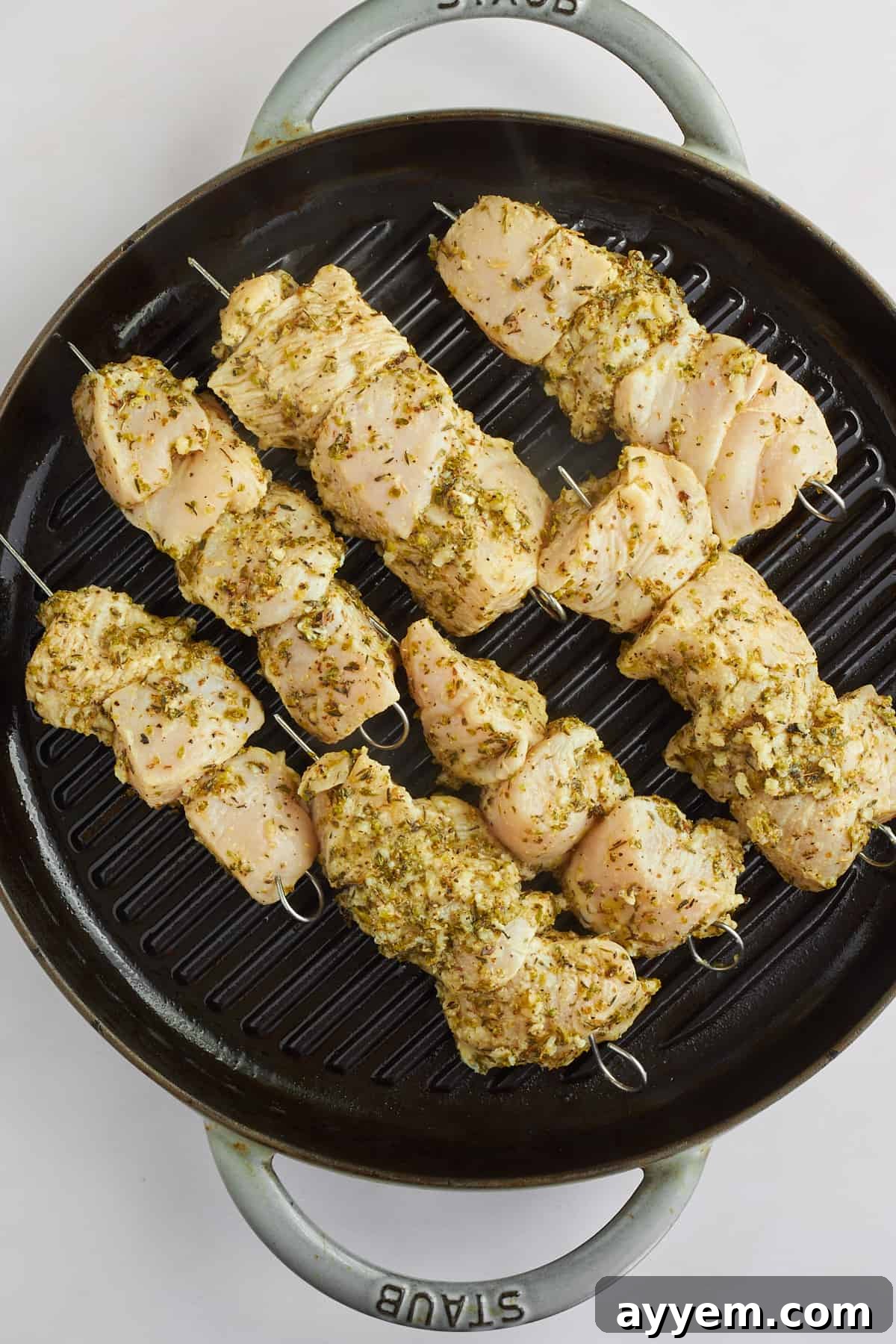 Chicken souvlaki skewers cooking on a grill pan.