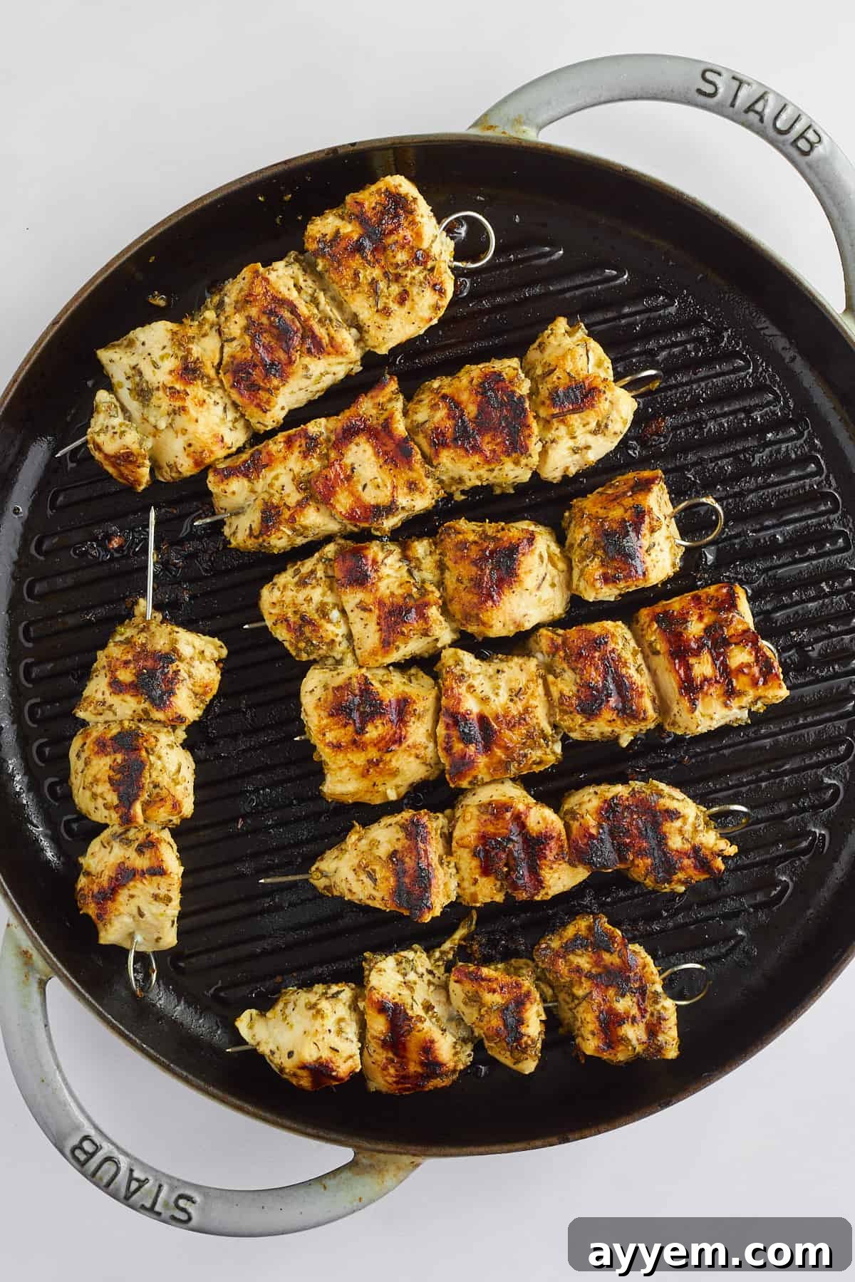 Grilled chicken souvlaki skewers on a grill pan.