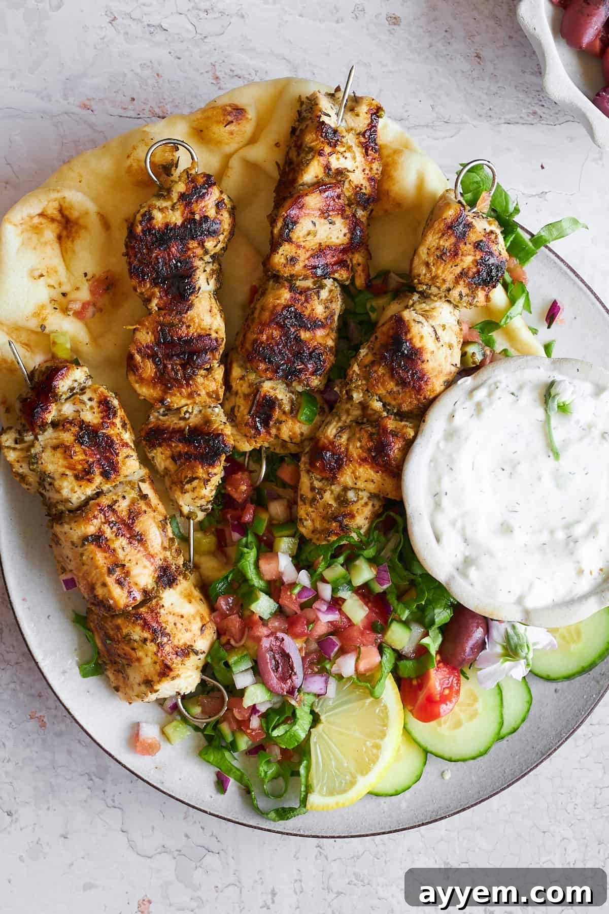 A plate of Greek chicken souvlaki skewers with salad.