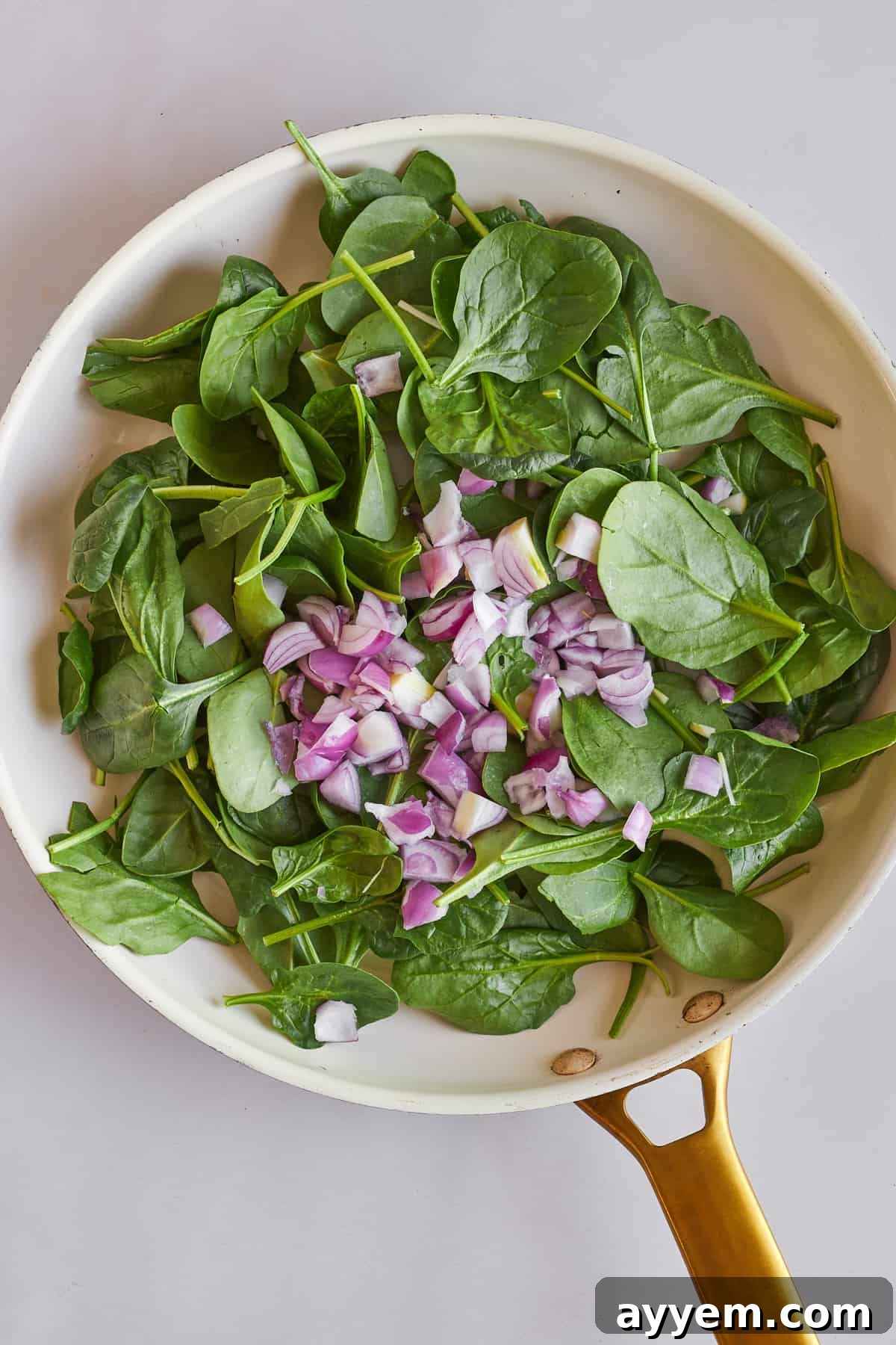 Fresh spinach and finely chopped shallots gently sautéing in a hot skillet, releasing their aromatic flavors.