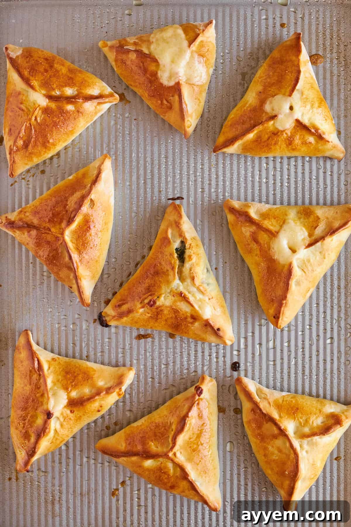 A tray of perfectly baked spinach and cheese fatayer, golden brown and inviting, fresh from the oven.