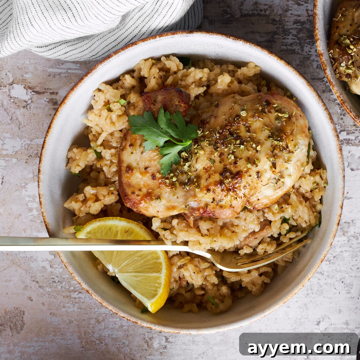 A bowl of Greek chicken and rice with a fork.