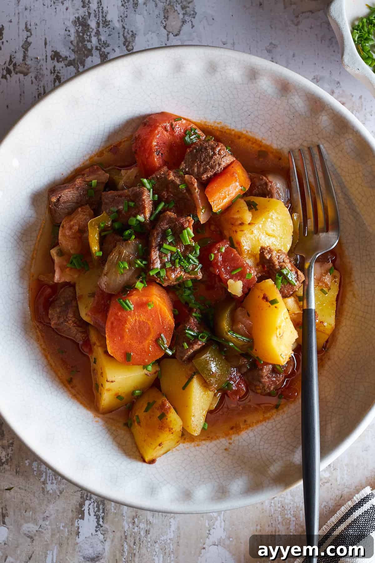 A steaming bowl of Easy Baked Beef Stew, garnished with fresh herbs, ready to be enjoyed as a hearty and comforting meal.