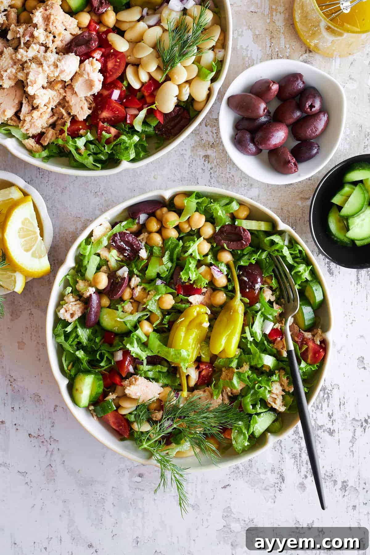 A beautifully presented bowl of Mediterranean tuna salad, ready to be enjoyed, with a fork tucked into the side.