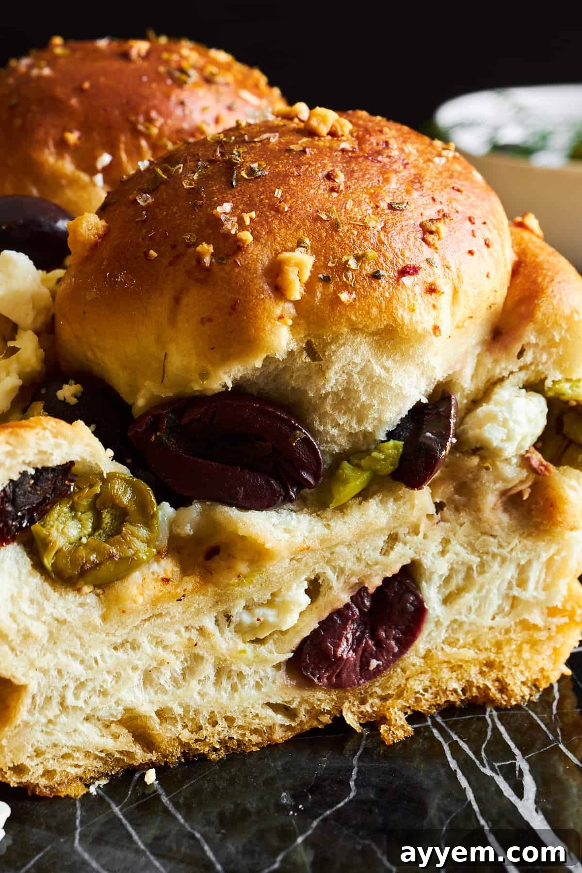 A close-up view of the golden-brown crust and flavorful toppings of the baked pull-apart olive bread.