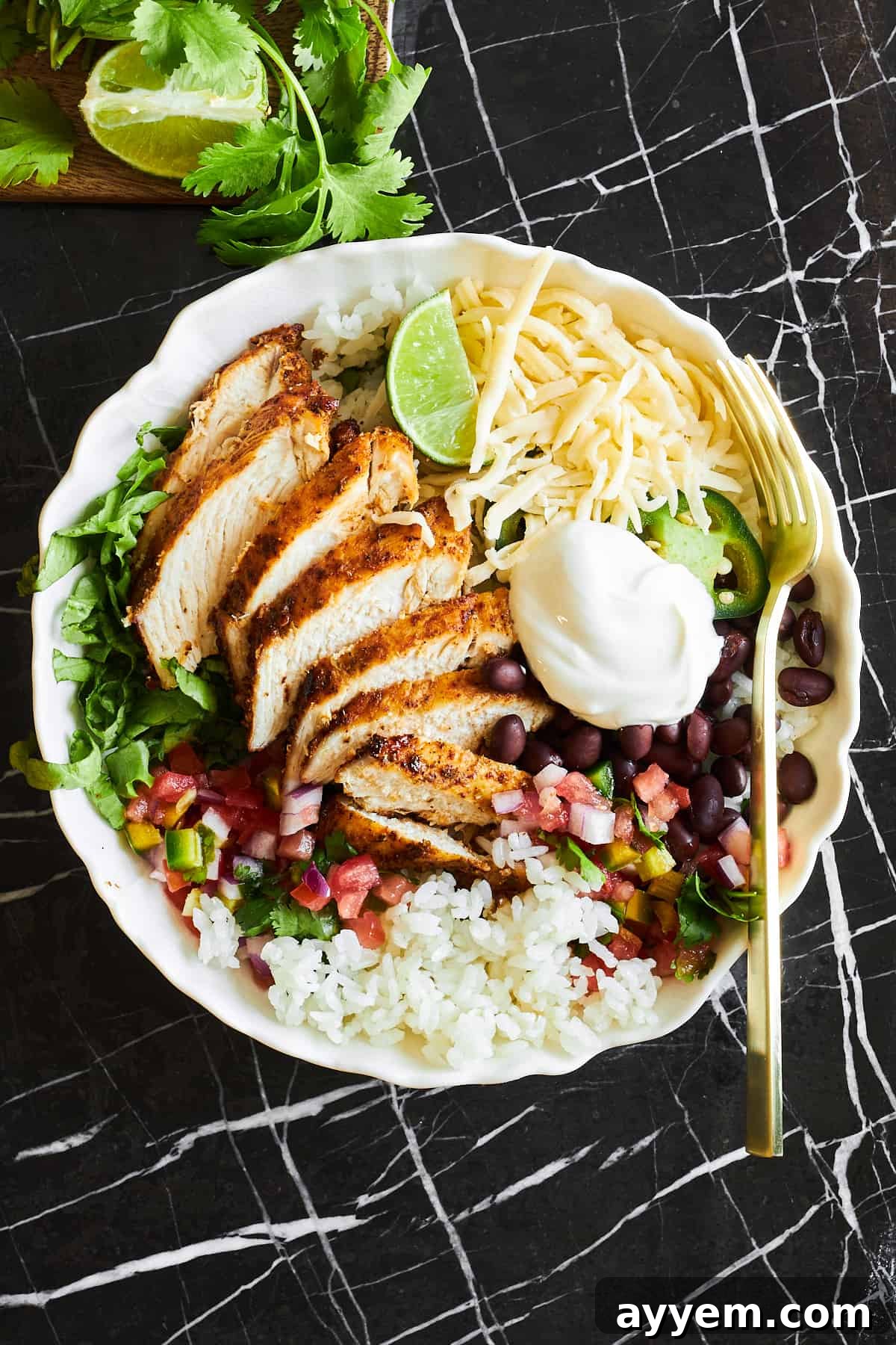 A copycat chipotle chicken burrito bowl with a fork on top. 