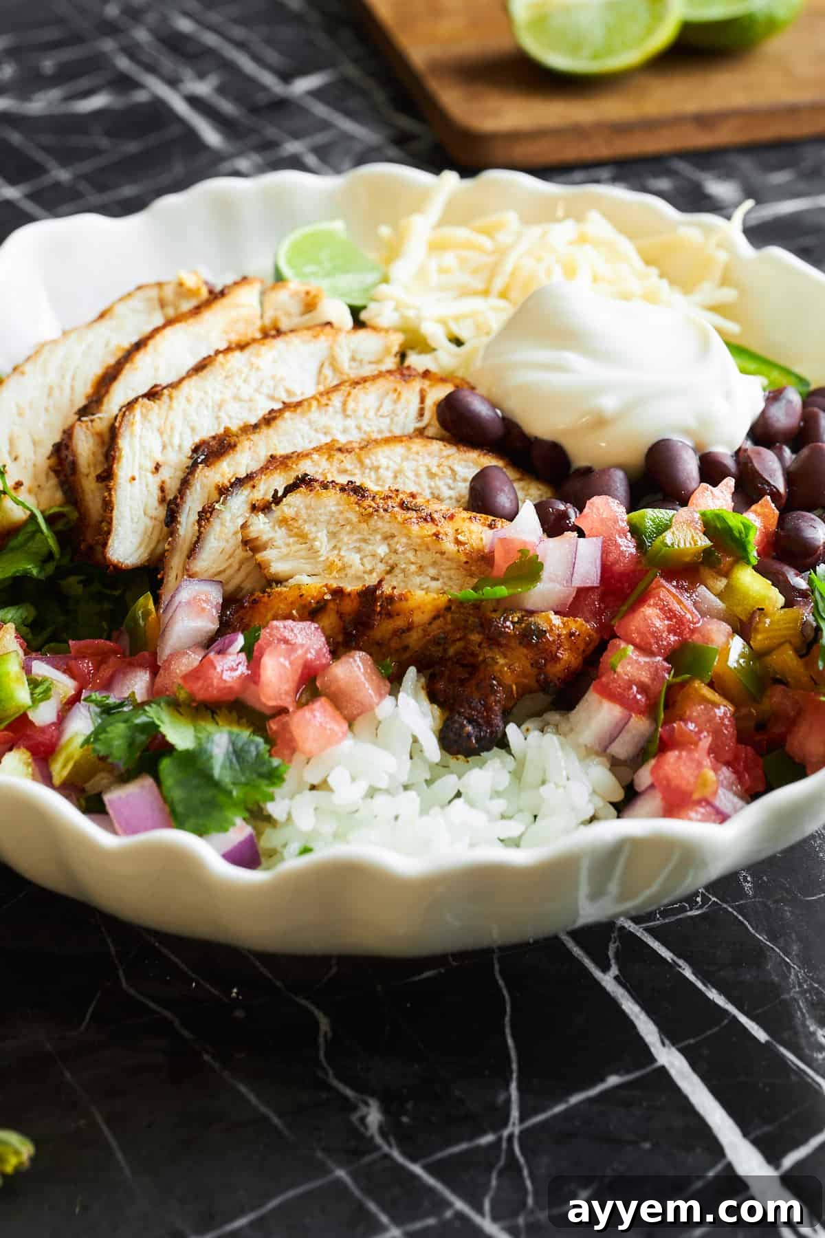 A homemade chipotle chicken burrito bowl with rice, black beans, cheese, salsa, and sour cream. 
