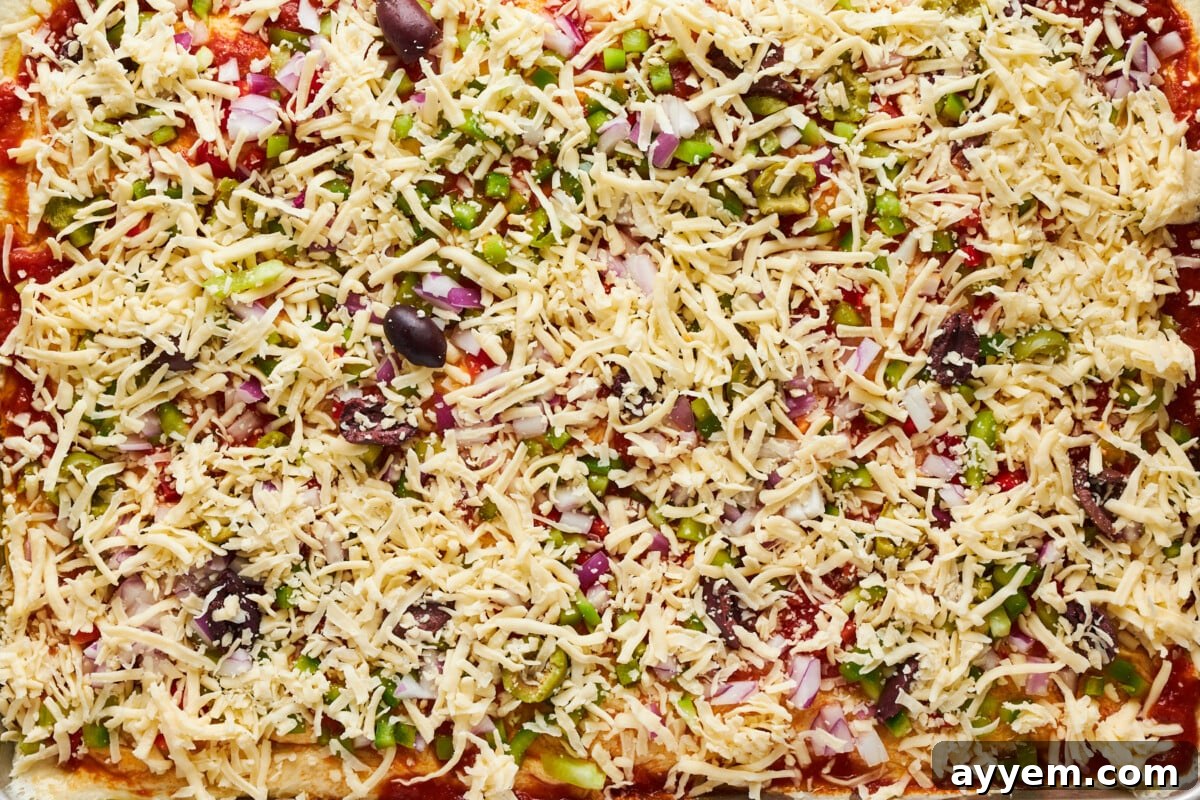 Pizza with all toppings including shredded mozzarella cheese, ready for baking.