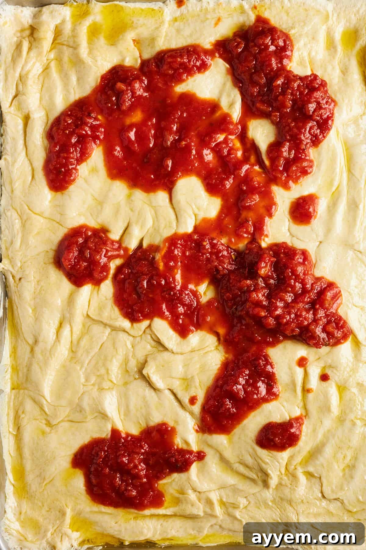 Pizza crust made from dinner rolls, topped with a rich marinara sauce.