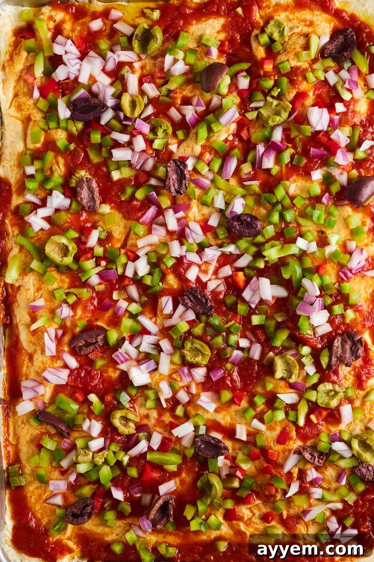 Dinner roll pizza crust topped with marinara sauce, colorful peppers, onions, and Kalamata olives.