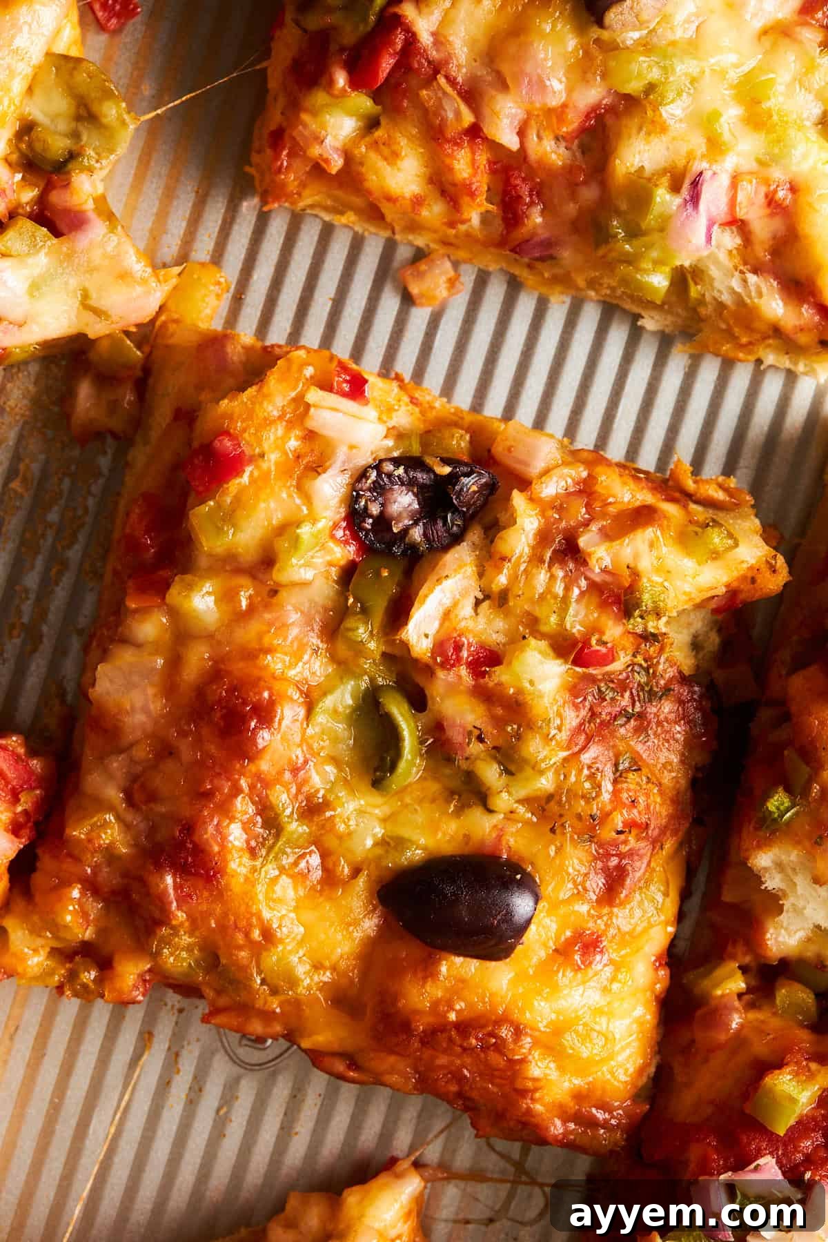 A perfectly baked slice of easy sheet pan pizza, showcasing the crispy crust and melted toppings.