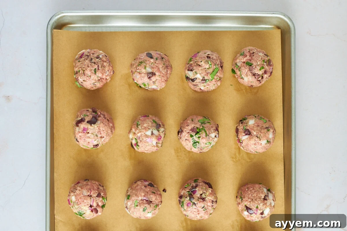 Raw beef meatballs on a baking sheet.