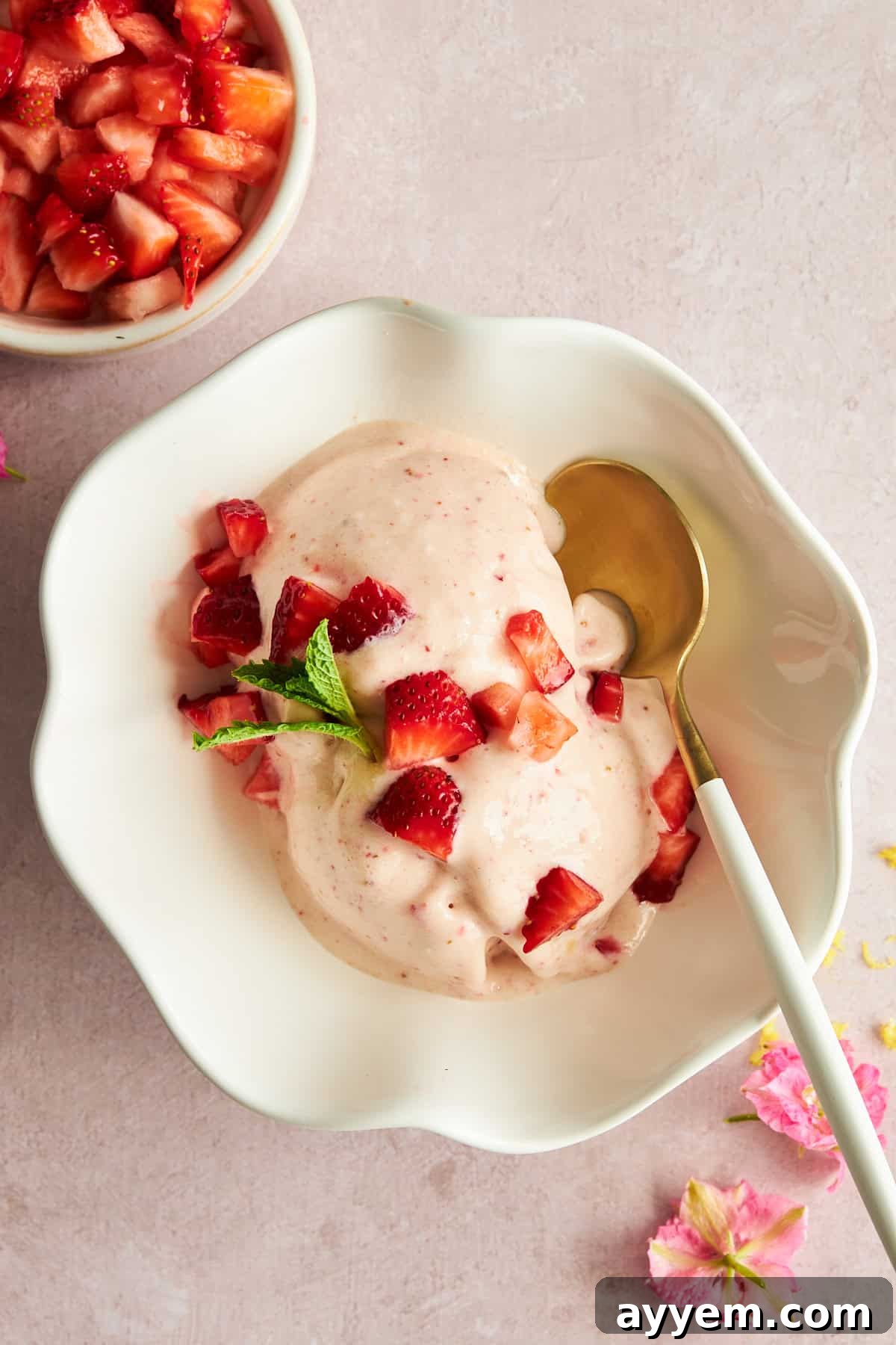 A scoop of creamy cottage cheese ice cream with fresh strawberries on top.