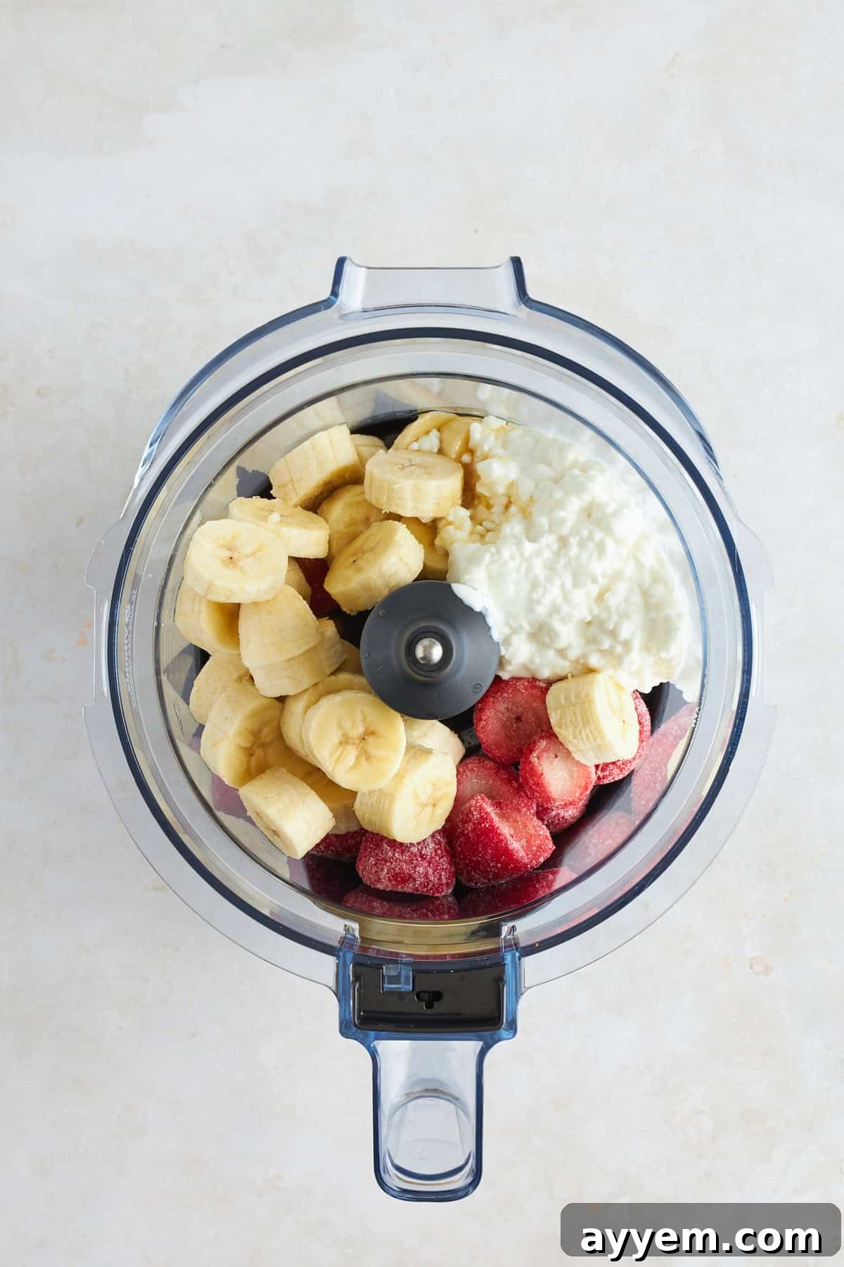 A blender jar filled with the creamy, pink cottage cheese ice cream mixture before freezing.
