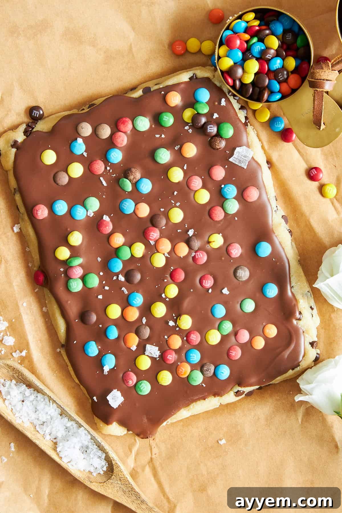 An overhead view of a freshly prepared slab of cookie dough bark, showcasing its rich chocolate layer studded with mini M&Ms, before being cut.