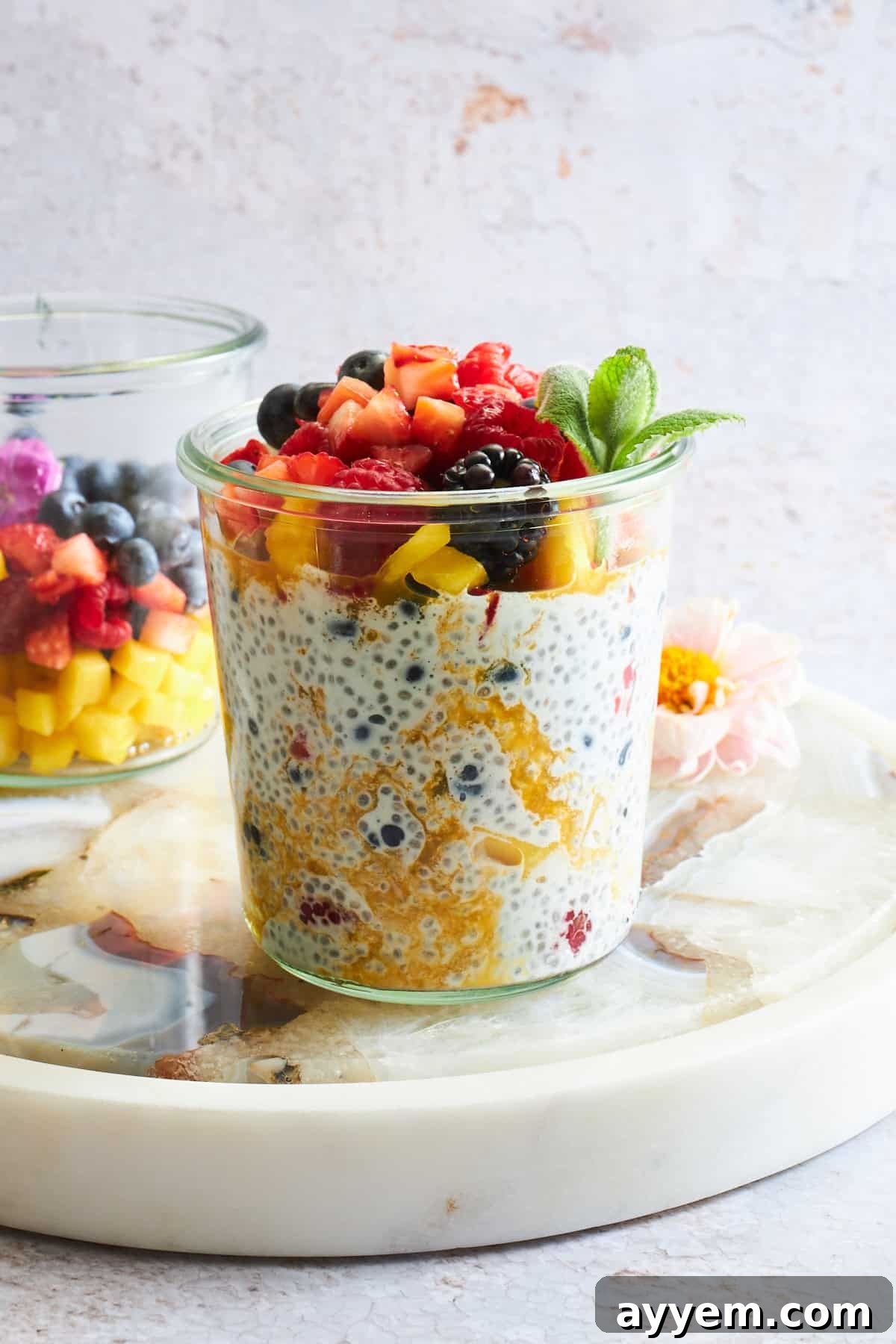Tropical Mango Chia Pudding with Fresh Fruit Medley 5 A jar of mango chia pudding topped with fruit salad.