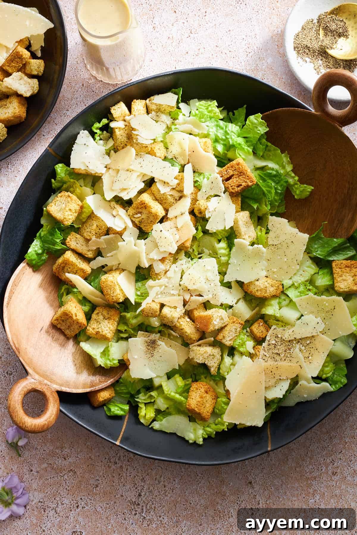 An overhead shot of a large bowl filled with chopped romaine lettuce, shredded Parmesan cheese, and golden croutons, ready for dressing.