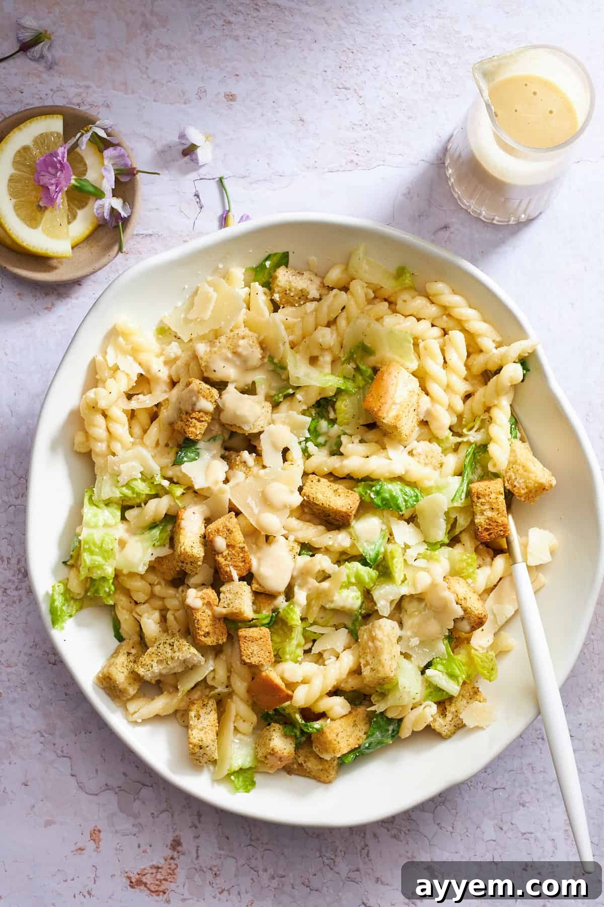 Zesty Caesar Pasta Bowl 2 A bowl of Caesar pasta salad with a fork on the side.