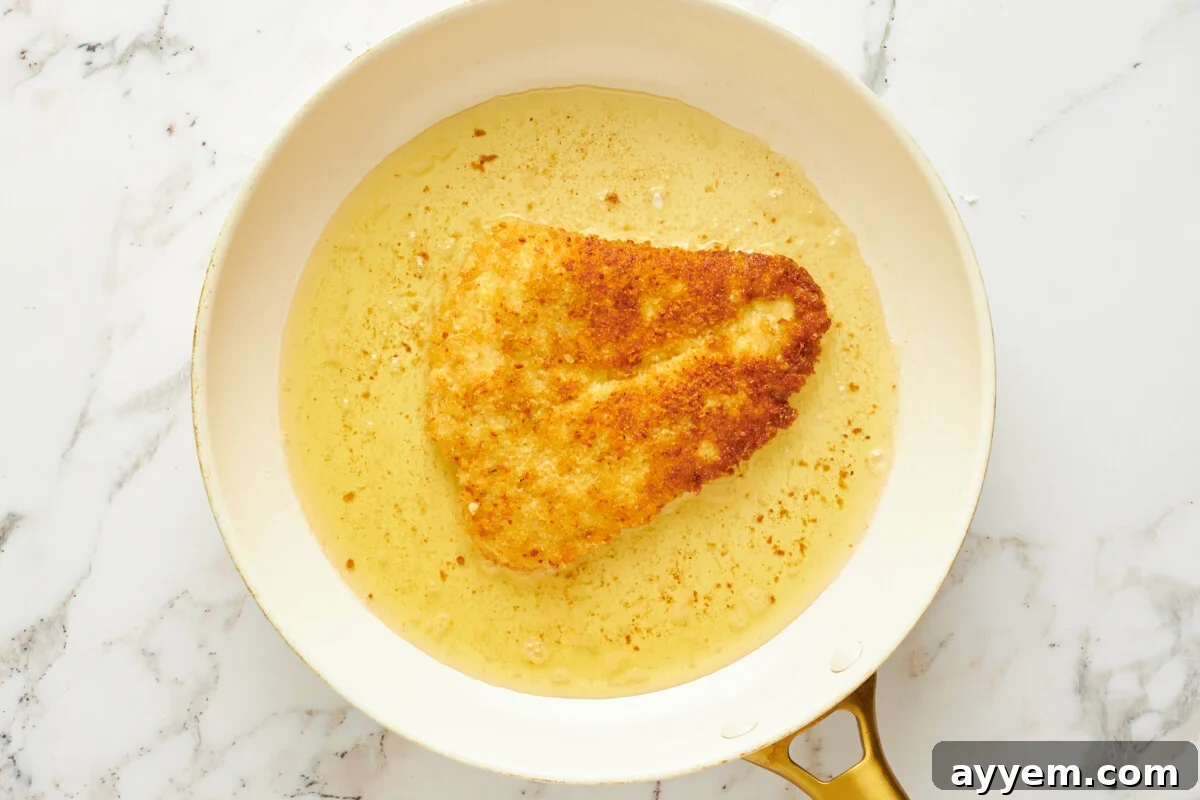 Breaded chicken cooking in a skillet.