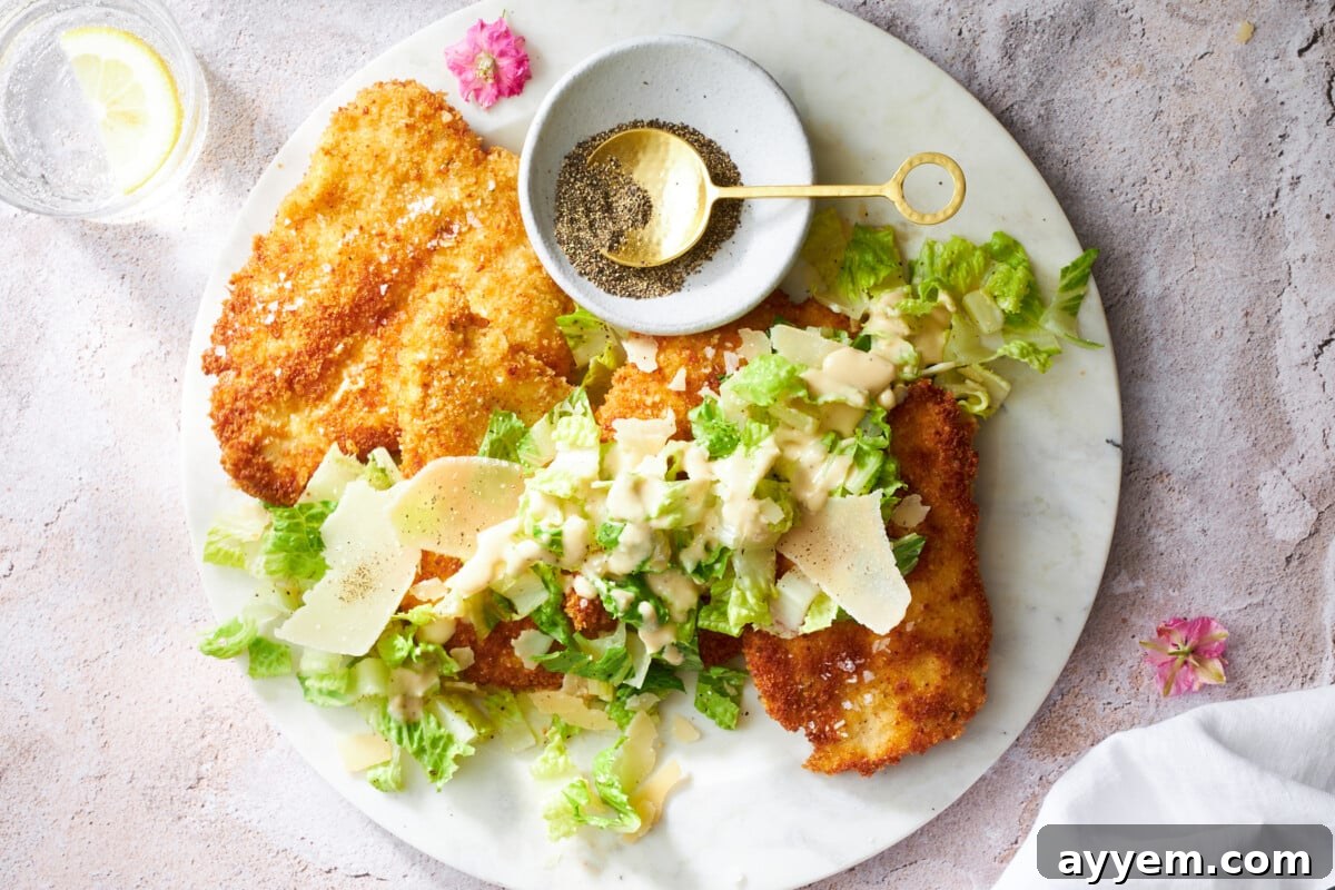 A plate of chicken Milanese topped with Caesar salad.