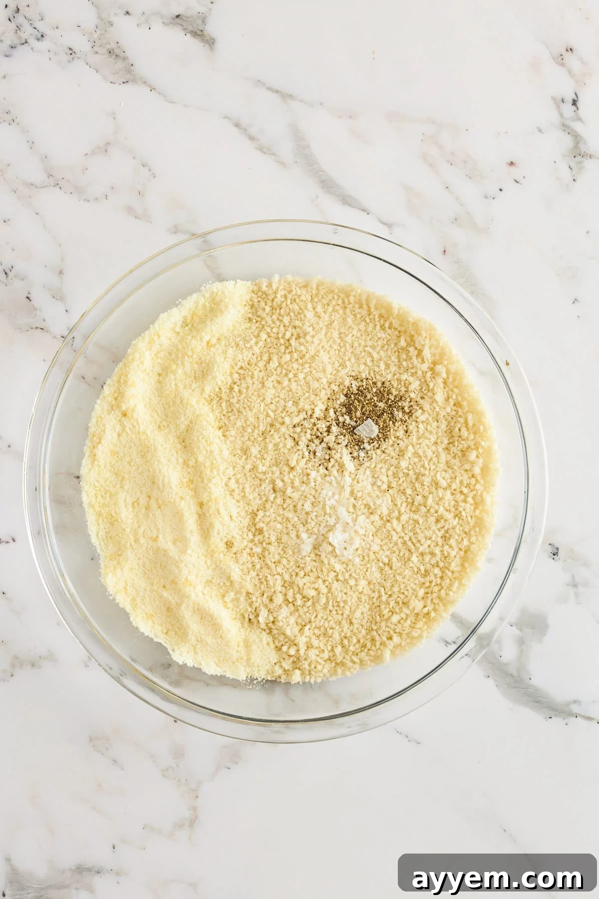 Golden Chicken Milanese with Zesty Caesar Salad 4 A second bowl containing a finely mixed blend of Panko breadcrumbs, grated Parmesan cheese, oregano, garlic powder, and smoked paprika, prepared for the final breading stage.