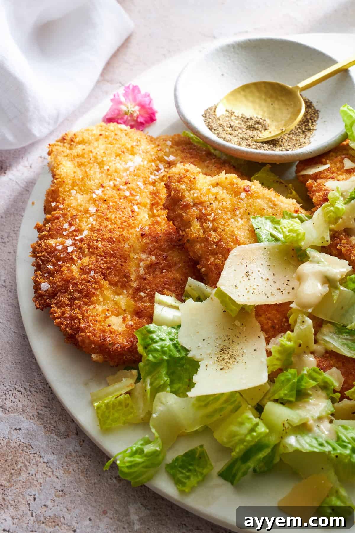 Golden Chicken Milanese with Zesty Caesar Salad 10 A perfectly plated chicken Milanese, golden and crispy, garnished with fresh herbs and a vibrant Caesar salad on the side.
