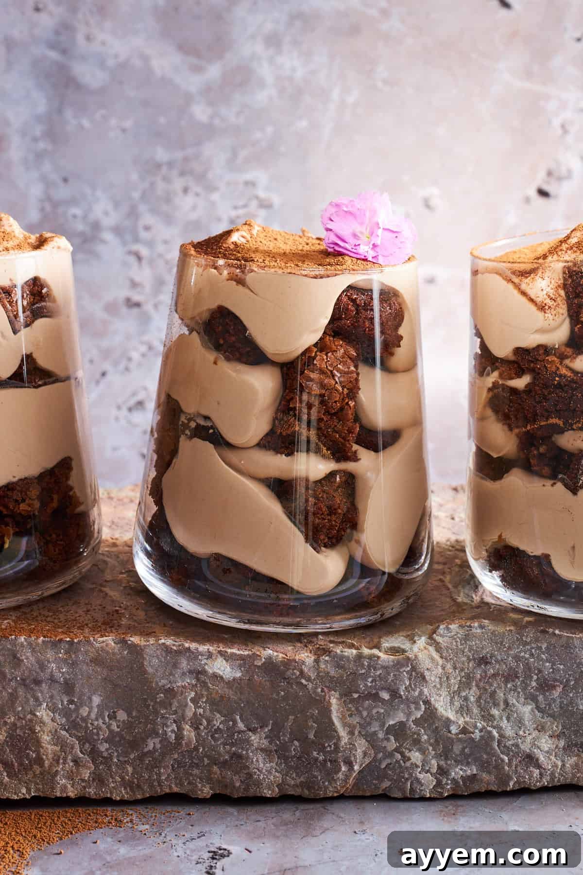 Three tiramisu brownie parfaits, beautifully layered and dusted with cocoa.