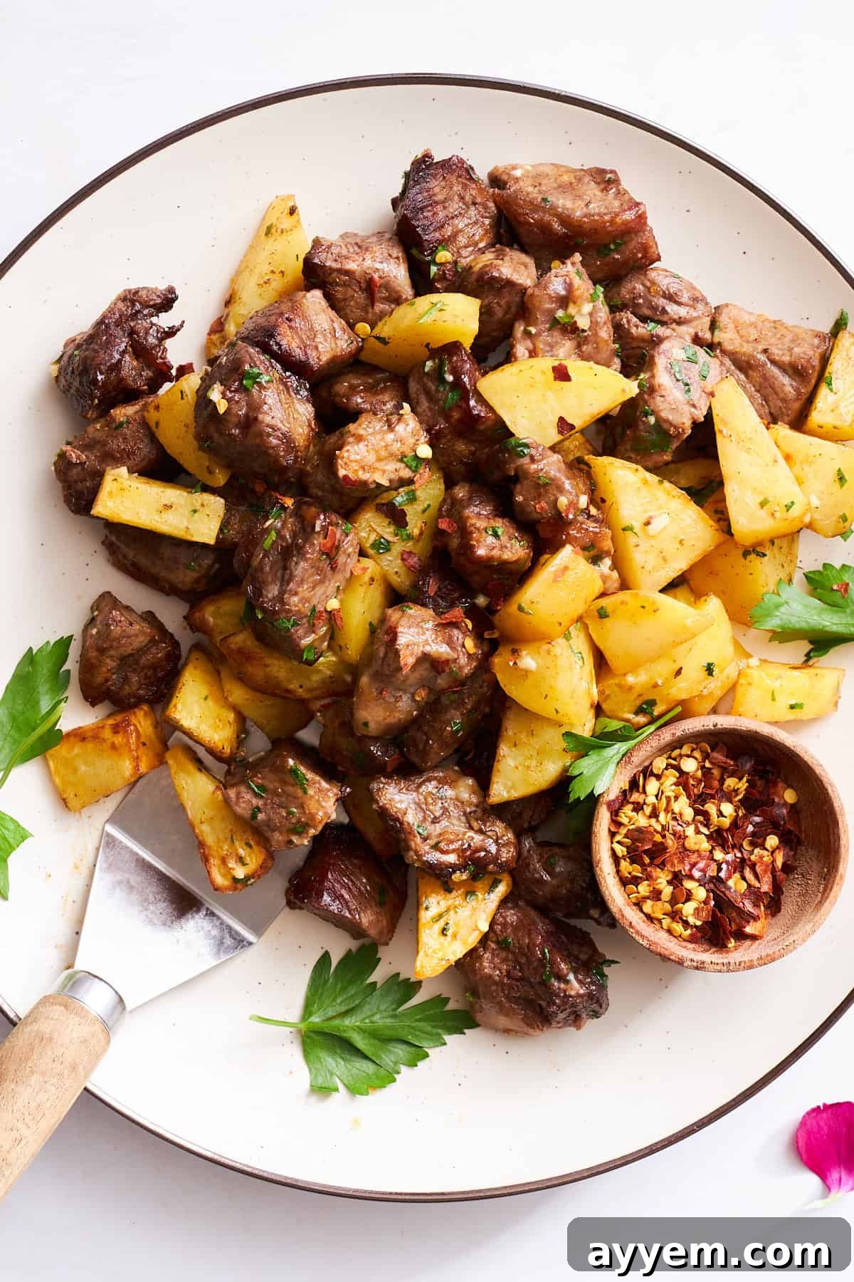 A plate of air fryer garlic steak bites and potatoes, perfectly cooked and garnished with fresh parsley.