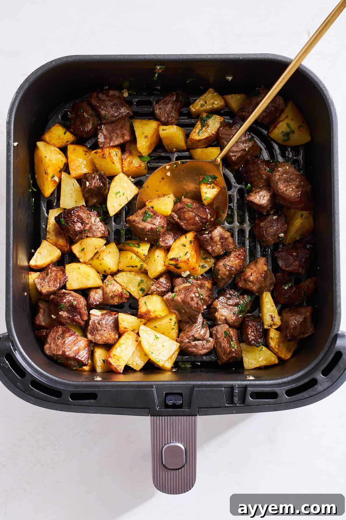 Cooked steak and potato pieces being tossed with a rich garlic butter sauce in a skillet, ready to serve.