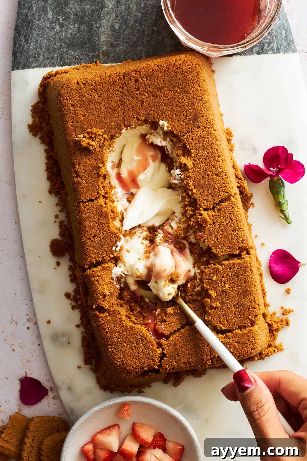 A spoon digging into the creamy center of an upside-down cheesecake with a Biscoff cookie crust.